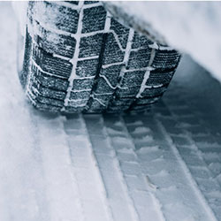 A close up of an all season tire in the snow.