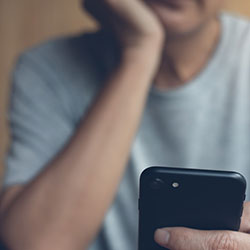 A man, bored, looking at his phone to pass the time.