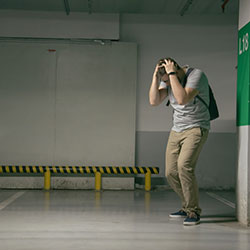 A young man at the parking spot in the underground parking garage where his car was parked but has since been stolen