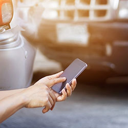 A close-up of a hand calling on their smartphone after being in a collision.