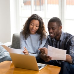 A couple, sitting on the couch, reviewing their paperwork's fine print.