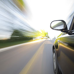 A car driving fast on a road with the scenery on the sides blurred.