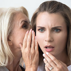 A woman telling another woman, likely her daughter, a secret.