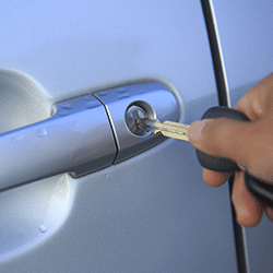 A person unlocking the door to their vehicle.